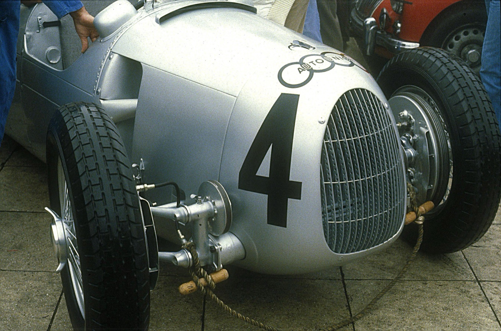 Nose of a silver Auto Union Type C numbered 4, showing the radiator grille, the trailing-arm front suspension and the four-ring badge