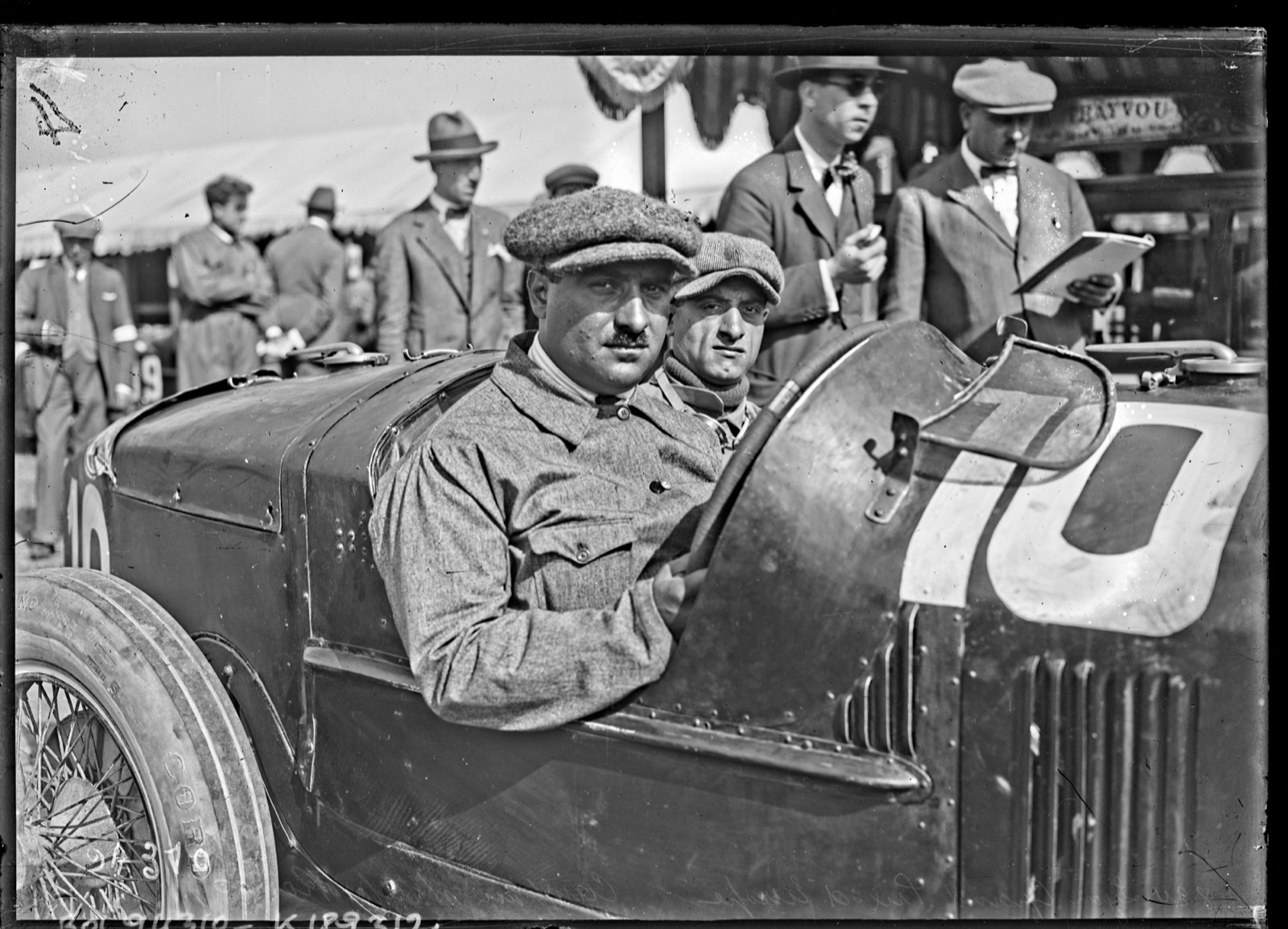 Giuseppe Campari seated in the dark Alfa Romeo P2 numbered 10, with a second man beside him, at the 1924 weighing-in at Lyon
