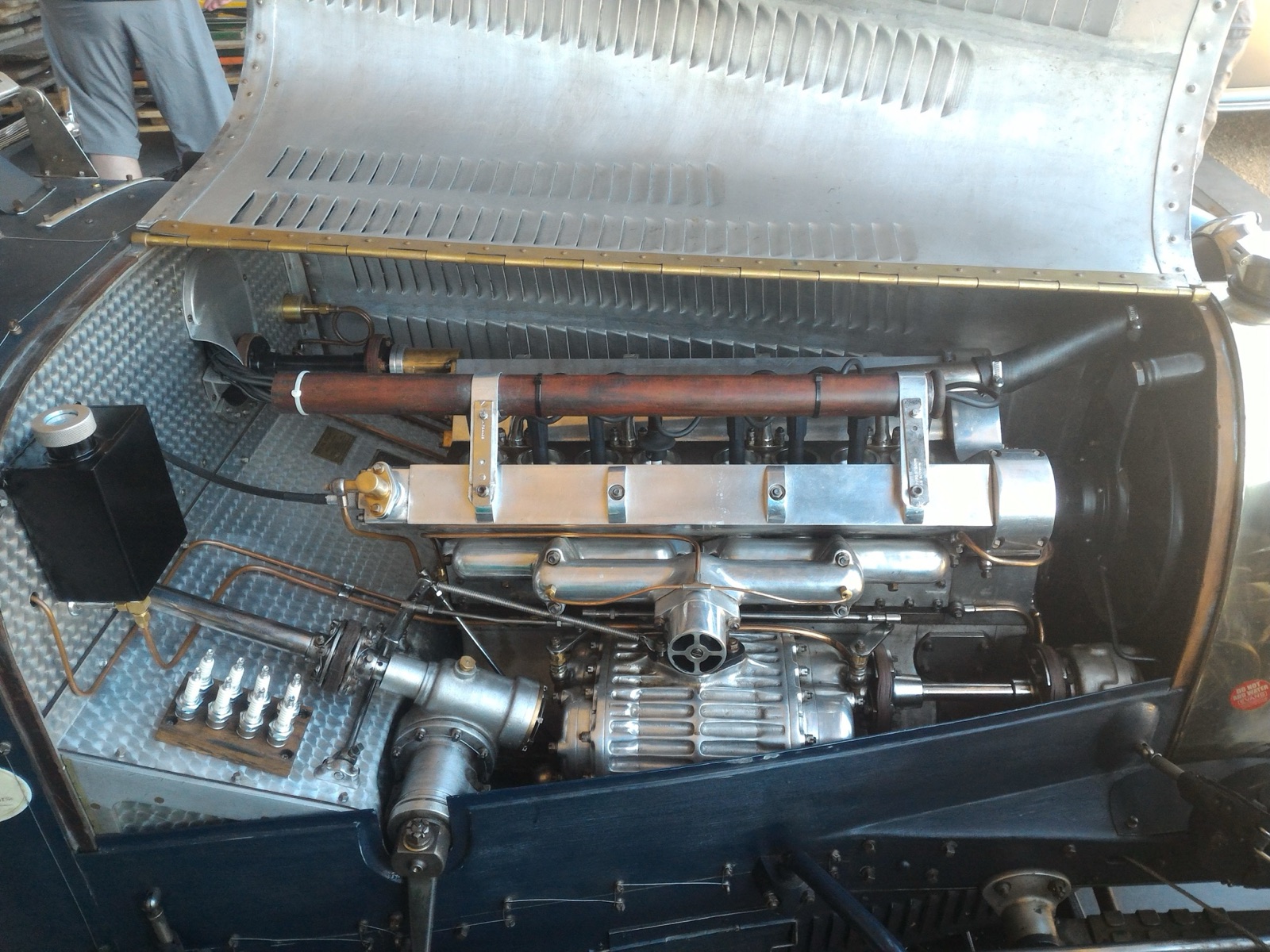 Engine bay of a supercharged Bugatti Type 35 with the bonnet open, showing the finned Roots blower below the straight-eight block