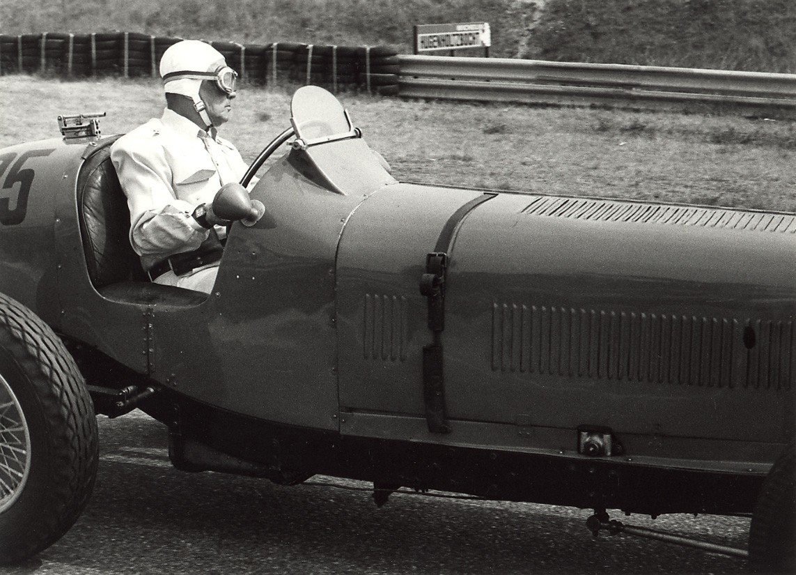 Black-and-white photograph of Prince Bira in a white helmet, goggles and white overalls at the wheel of an ERA B-type numbered 25 at Zandvoort