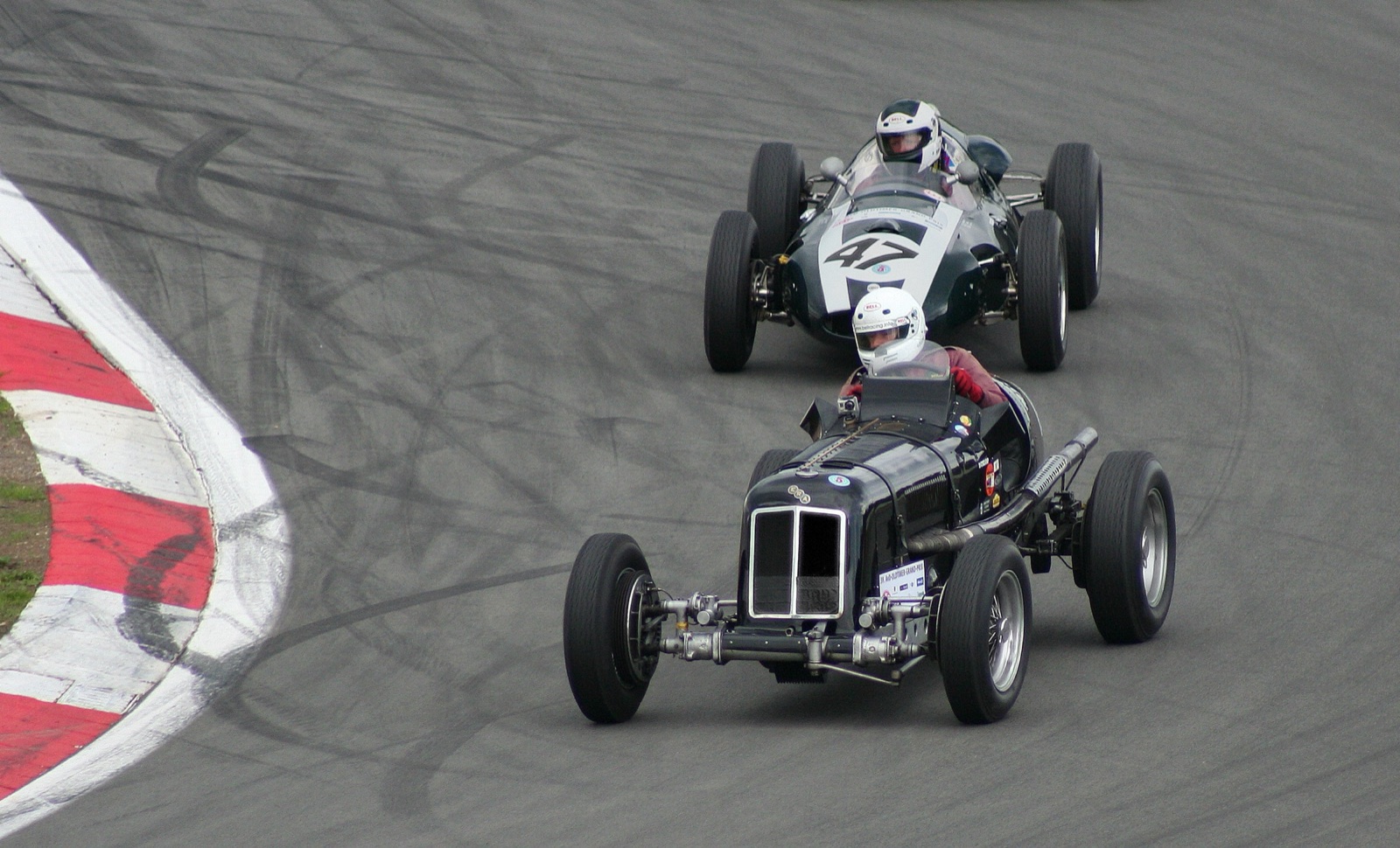 Black ERA R4D cornering towards the camera, showing its independent front suspension, followed by a green Cooper single-seater