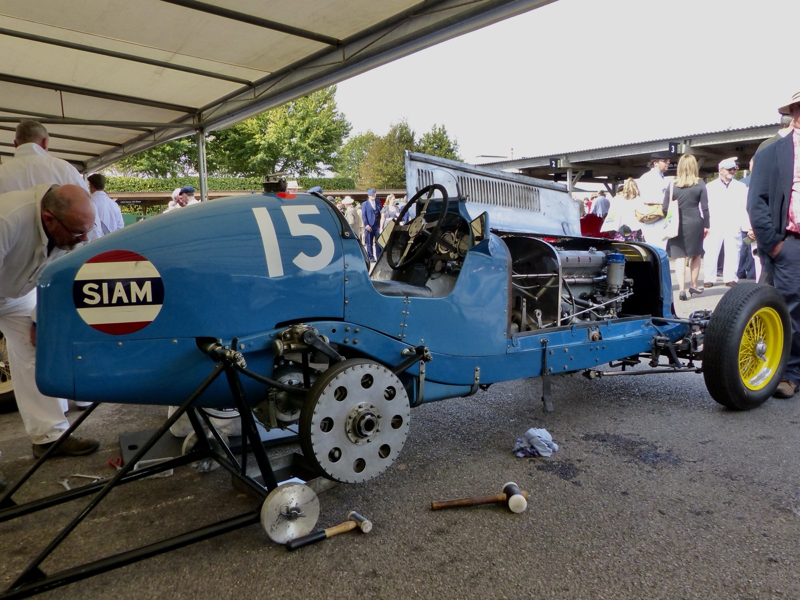 Blue ERA R5B Remus with yellow wheels and a SIAM roundel on its tail, on stands in the Goodwood paddock with its bonnet open