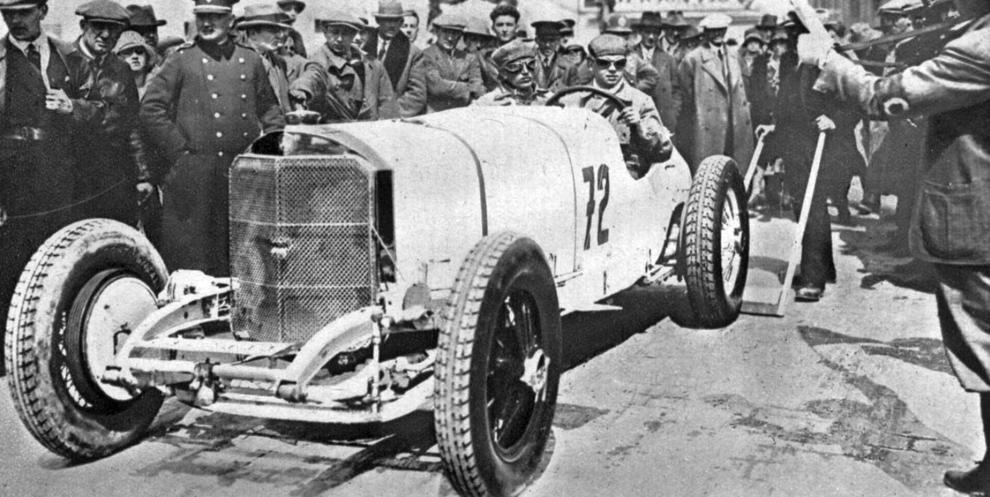 Rudolf Caracciola in goggles at the wheel of a white Mercedes-Benz SSK numbered 72, without wings, surrounded by officials and spectators